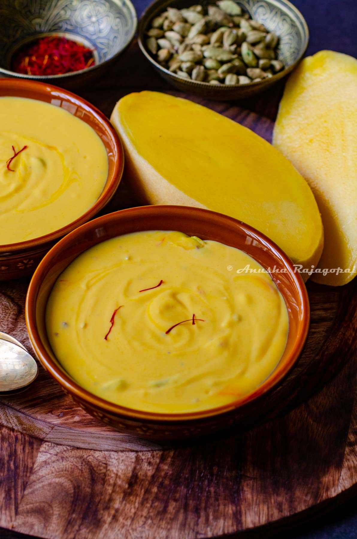 Aamrakhand served in a wooden platter with cut mangoes, saffron and cardamom