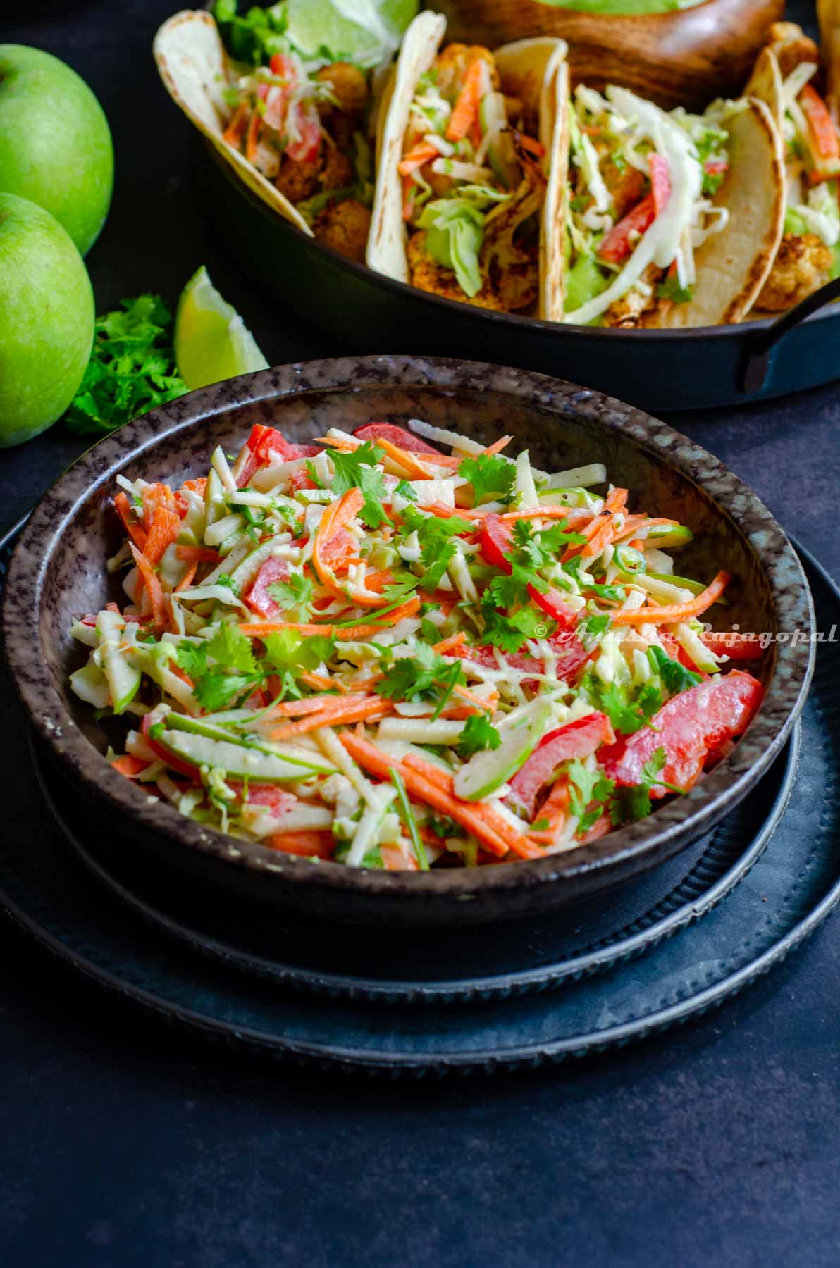 mayo free taco slaw served in a black bowl along side tacos. slaw made with green apples.