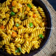 Vegetarian curry pasta with vegetables and chickpeas served in a bowl.