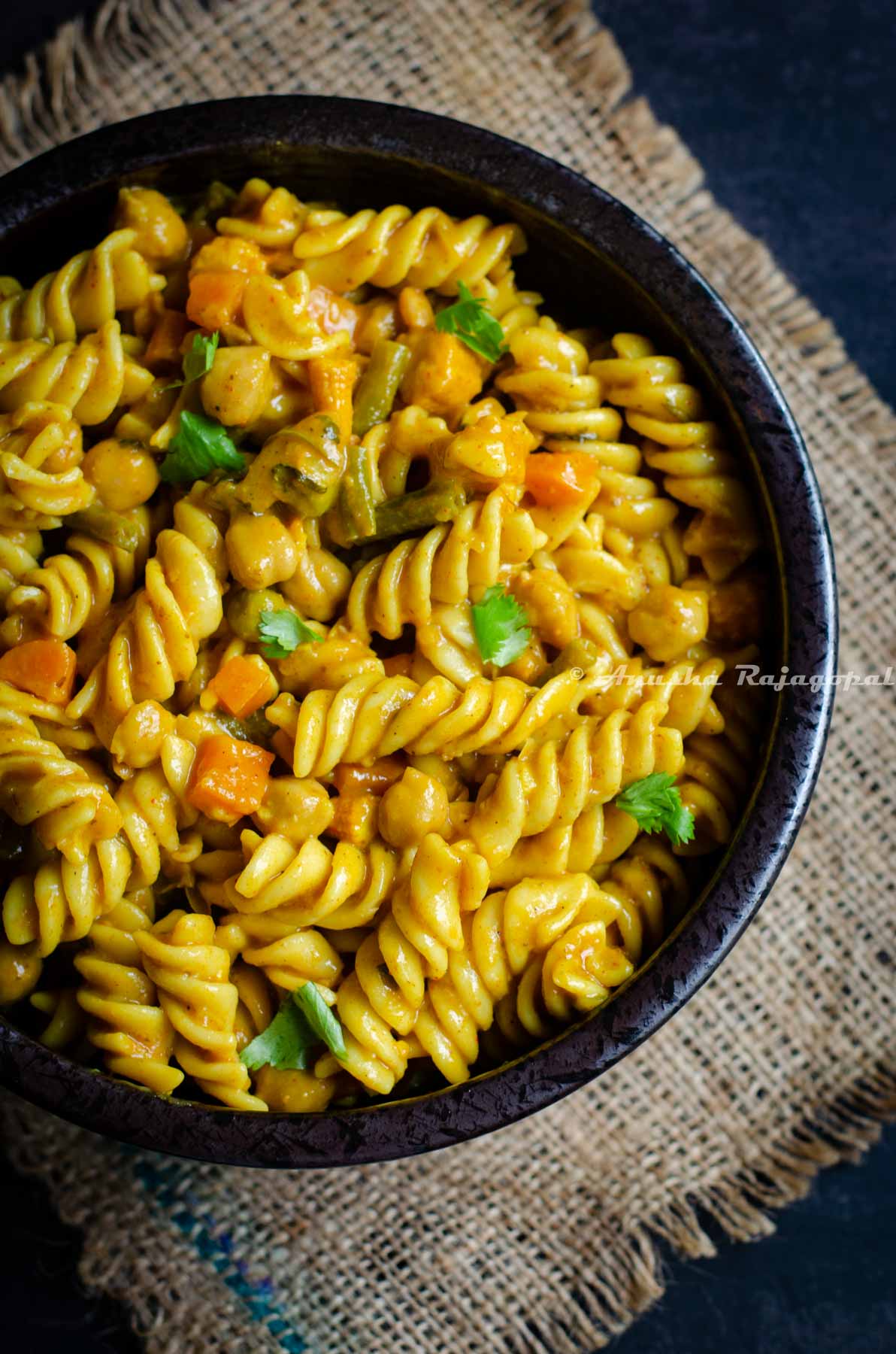 Vegetarian curry pasta with vegetables and chickpeas served in a bowl.